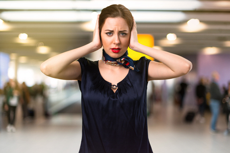 Pretty stewardess covering her ears inside the airportの写真素材