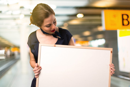 Pretty stewardess holding an empty placard inside the airportの写真素材