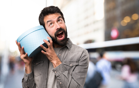 Surprised Handsome man with beard holding a gift at outdoorの写真素材