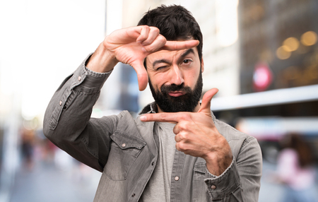 Handsome man with beard focusing with his fingers at outdoorの写真素材