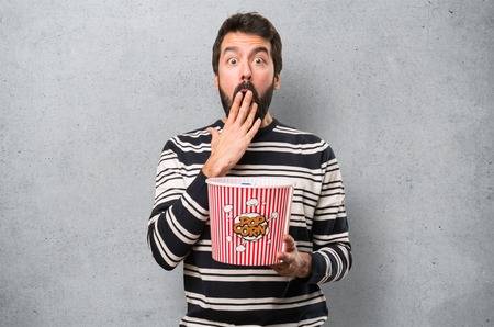 Surprised Man with beard eating popcorns on textured backgroundの写真素材