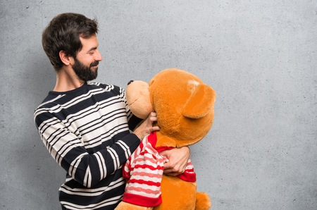Man with beard playing with stuffed animal on textured backgroundの写真素材