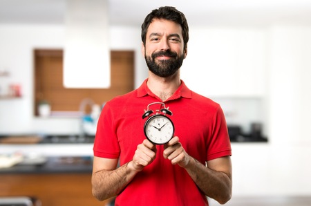 Happy Handsome man holding vintage clock inside houseの写真素材
