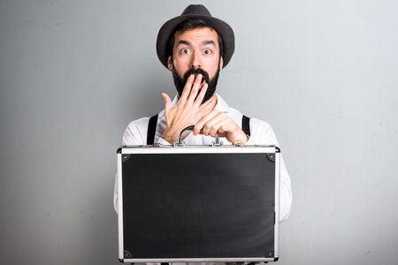 Hipster man with beard holding a briefcase on grey backgroundの写真素材