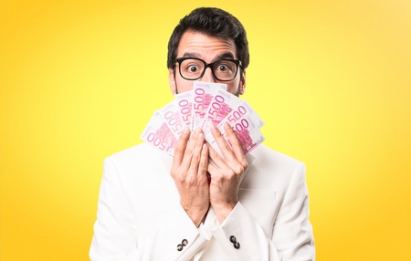 Brunette man with glasses taking a lot of money on colorful backgroundの写真素材