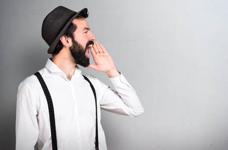 Hipster man with beard shouting on grey backgroundの写真素材