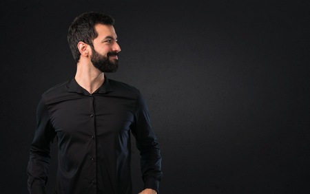 Handsome man with beard looking lateral on black background