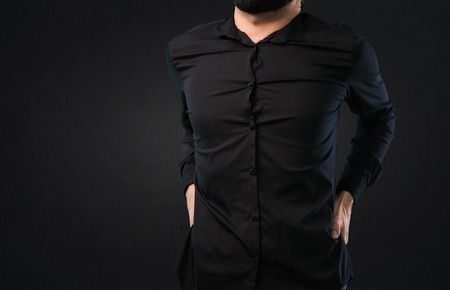 Handsome man with beard with back pain on black backgroundの写真素材