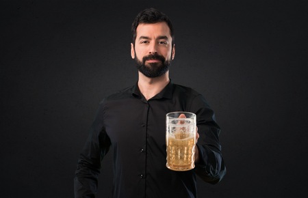 Handsome man with beard drinking beer on black backgroundの写真素材