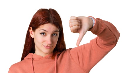Young redhead girl with pink sweatshirt showing thumb down sign with negative expression. Sad expression on isolated white backgroundの写真素材