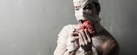 Terrorific mummy eating a heart on textured wall background.  Halloween holidaysの写真素材