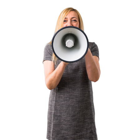 Middle-age blonde woman shouting through a megaphone to announce something on isolated white backgroundの写真素材