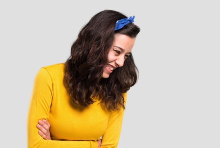 Young girl with yellow sweater and blue bandana on her head keeping the arms crossed while smiling on isolated grey backgroundの写真素材