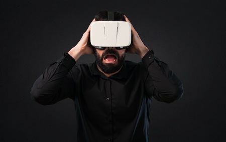 Handsome man with beard using VR glasses on black background