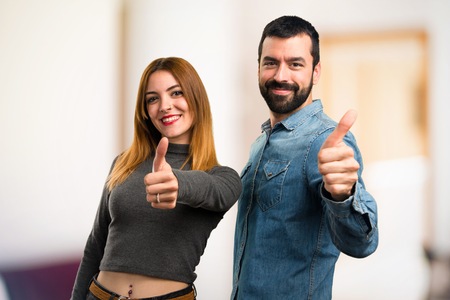 Man and woman with thumb up on unfocused backgroundの写真素材