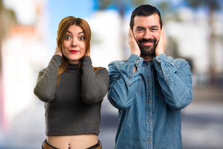 Man and woman covering their ears on unfocused backgroundの写真素材