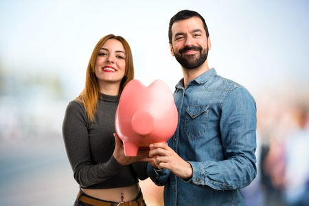 Man and woman holding a piggybank on unfocused backgroundの写真素材