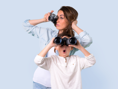 Mother and daughter with black binoculars on blue backgroundの写真素材
