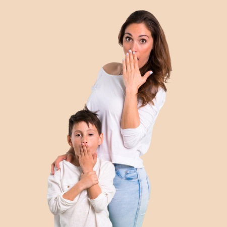 Mother and son with surprise and shocked facial expression on ocher backgroundの写真素材