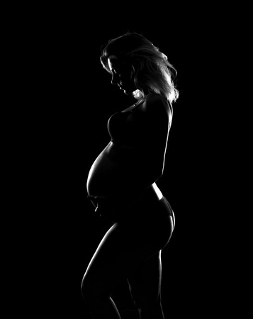 Artistic silhouette of blonde pregnant woman on isolated backgroundの写真素材