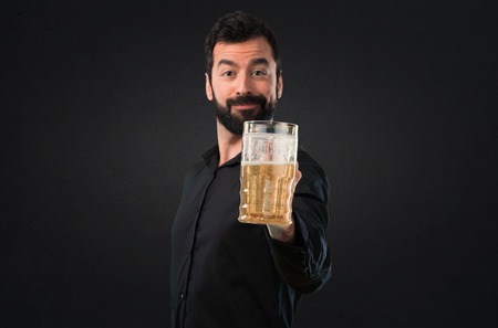 Handsome man with beard drinking beer on black backgroundの写真素材