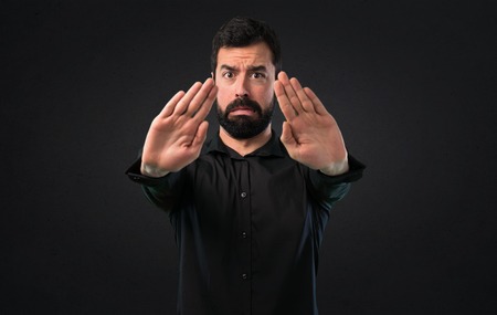 Handsome man with beard making stop sign on black backgroundの写真素材
