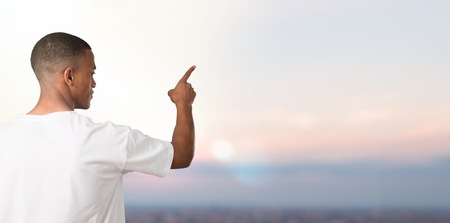 Young african american man pointing back with the index finger on sunset backgroundの写真素材
