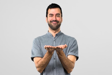 Handsome man holding copyspace imaginary on the palm on grey backgroundの写真素材