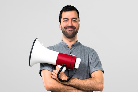 Handsome man holding a megaphone on grey backgroundの写真素材