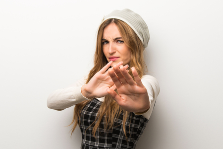 Fashionably woman wearing hat is a little bit nervous and scared stretching hands to the frontの写真素材