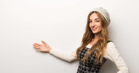 Fashionably woman wearing hat pointing back and presenting a productの写真素材
