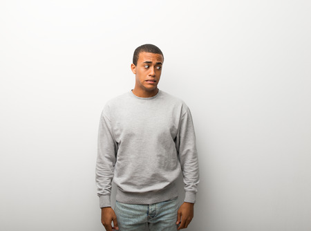 African american man on white wall background is a little bit nervous and scared pressing the teeth