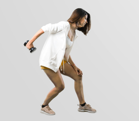 Full body of Sport woman making weightlifting on grey backgroundの写真素材