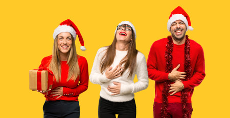 A group of people Blonde woman dressed up for christmas holidays smiling a lot while putting hands on chest on yellow backgroundの写真素材