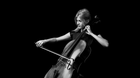 Young girl playing the cello on isolated black backgroundの写真素材