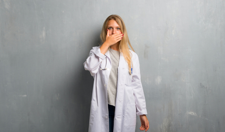 Young doctor woman covering mouth with hands for saying something inappropriateの写真素材
