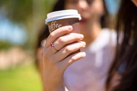 holding coffee in takeaway paper cupの写真素材