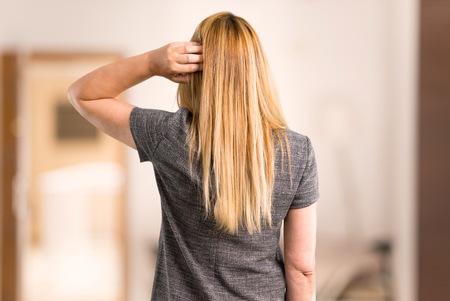 Middle age blonde woman with grey dress looking back inside a houseの写真素材