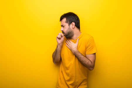 Man on isolated vibrant yellow color is suffering with cough and feeling badの写真素材