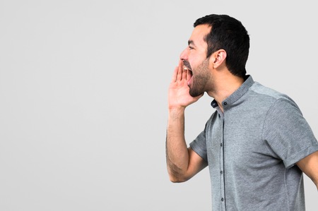 Handsome man shouting with mouth wide open on grey backgroundの写真素材