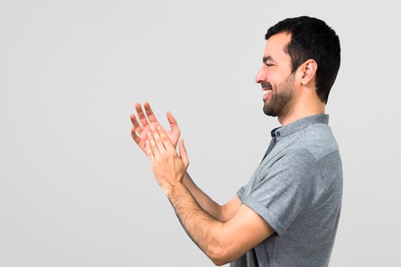 Handsome man applauding on grey backgroundの写真素材