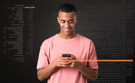 Young african american man sending a message or email with the mobileの写真素材