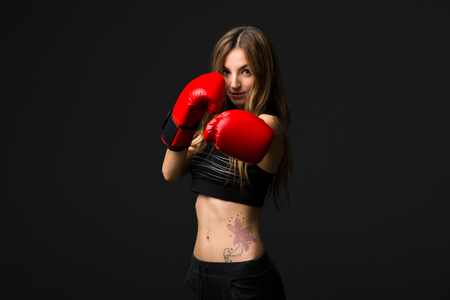 Sport woman with boxing gloves on dark backgroundの写真素材