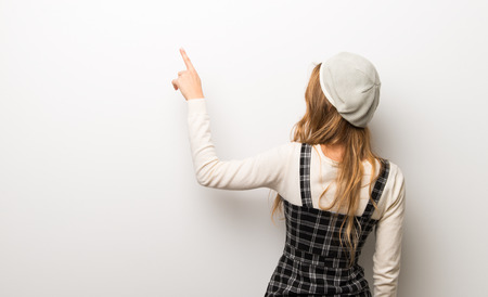 Fashionably woman wearing hat pointing back with the index fingerの写真素材