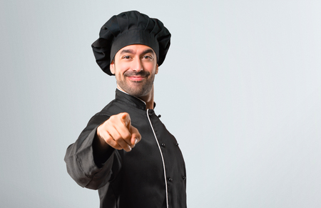 Chef man In black uniform points finger at you with a confident expression on grey backgroundの写真素材