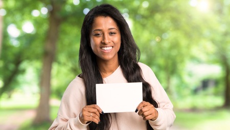 Young afro american woman holding a placard for insert a concept at outdoorsの写真素材