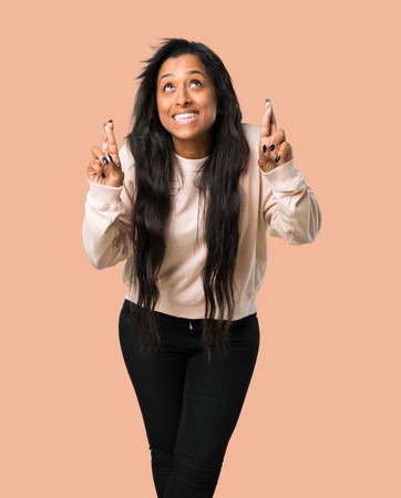 Young afro american woman with fingers crossing and wishing the best on isolated brown backgroundの写真素材