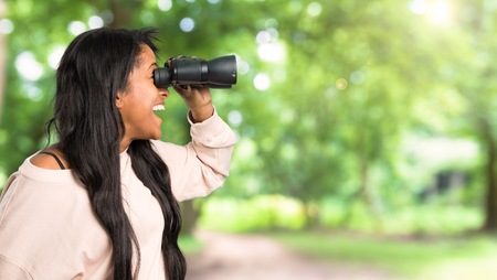 Young afro american woman and looking in the distance with binoculars at outdoorsの写真素材