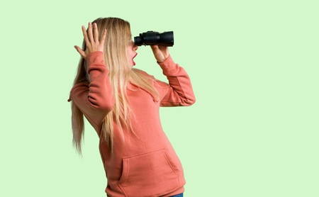 Young girl and looking in the distance with binoculars on green backgroundの写真素材