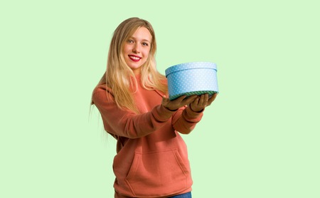 Young girl holding a gift in hands on green background